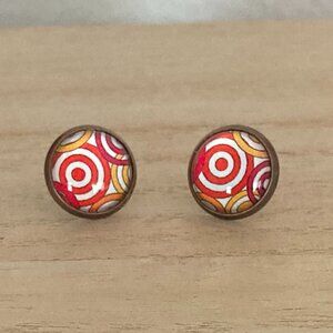 Stud earrings. Glass dome over a red, yellow and white pattern.